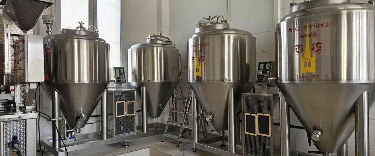 Cuve de fermentation en acier inoxydable dans une brasserie artisanale, avec équipements modernes et espace de production lumineux.